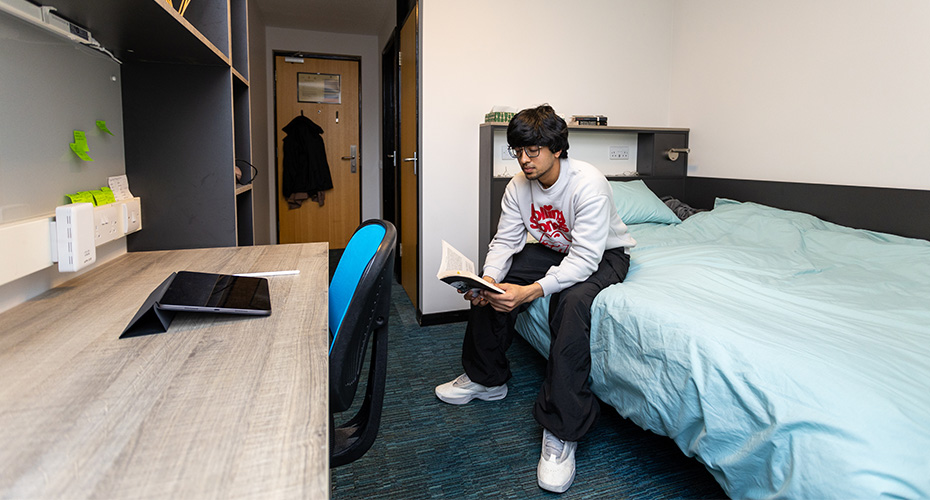 A student sat reading on a bed
