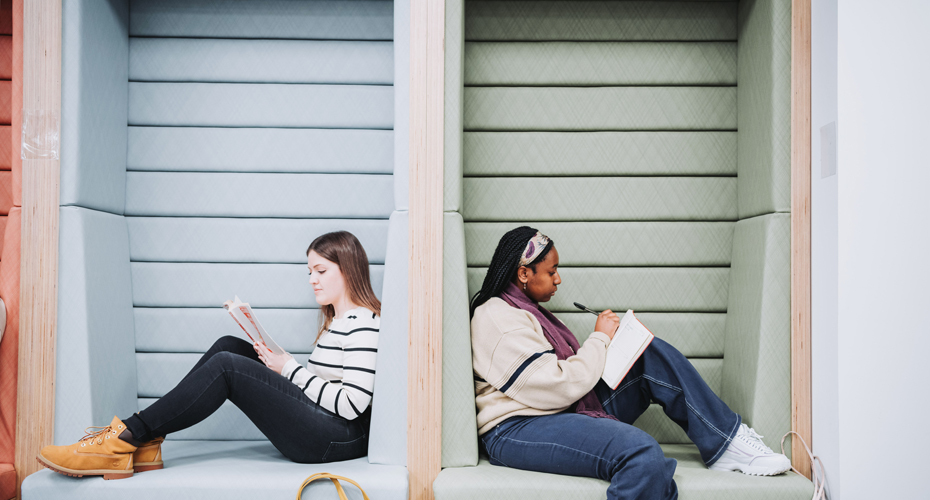 student sitting back to back in study booth